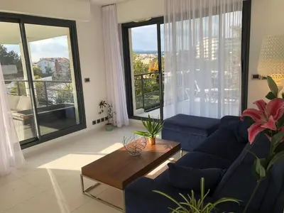 a living room with a blue couch and a table at Appartement montfleury, 2 terrasses, 2 chambres , 2 sdb , pkg privé piscine, 15 min walk to Croisette beach and Palais des festivals in Cannes