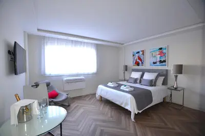 a white bedroom with a bed and a table at Studio Cannes Grand Hôtel Eider in Cannes