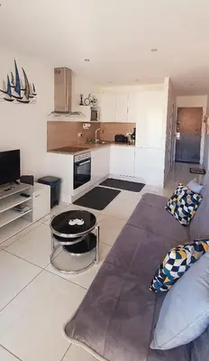 a living room with a couch and a kitchen at 2 pièces avec terrasse -Calme-Sans vis à vis-garage-centre de Cannes in Cannes