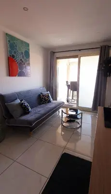 a living room with a blue couch and a table at 2 pièces avec terrasse -Calme-Sans vis à vis-garage-centre de Cannes in Cannes