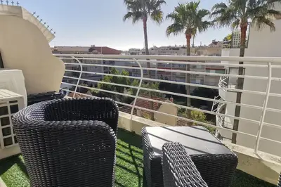 two wicker chairs sitting on a balcony with palm trees at Cannes Pointe Croisette studio plage 2 min à Pieds in Cannes