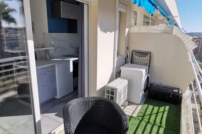 a balcony with a table and a chair and a kitchen at Cannes Pointe Croisette studio plage 2 min à Pieds in Cannes