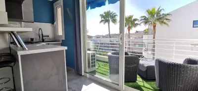 a kitchen with a view of a balcony with palm trees at Cannes Pointe Croisette studio plage 2 min à Pieds in Cannes
