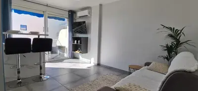 a living room with a couch and a large window at Cannes Pointe Croisette studio plage 2 min à Pieds in Cannes