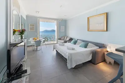 a living room with a bed and a television at Palais Miramar - Suite Blue Room - Vue Mer -Croisette Emplacement Unique - 20M Plage - WIFI - Clim in Cannes