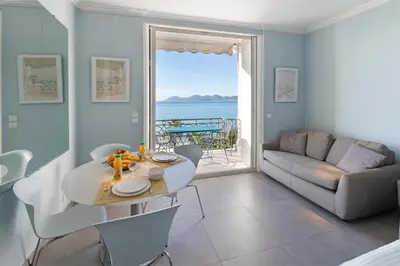 a living room with a table and a couch at Palais Miramar - Suite Blue Room - Vue Mer -Croisette Emplacement Unique - 20M Plage - WIFI - Clim in Cannes