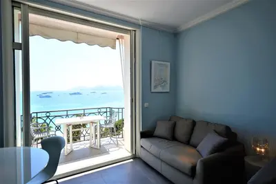 a living room with a couch and a large window at Palais Miramar - Suite Blue Room - Vue Mer -Croisette Emplacement Unique - 20M Plage - WIFI - Clim in Cannes