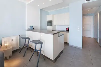 a kitchen with white cabinets and two stools in it at Palais Miramar - Suite Blue Room - Vue Mer -Croisette Emplacement Unique - 20M Plage - WIFI - Clim in Cannes