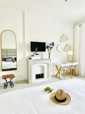 a white room with a bed and a mirror at Palais Miramar - Cannes Croisette - Across the Beach - Next to Carlton Hotel in Cannes