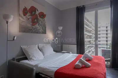 a bedroom with a bed with a red blanket and a window at Palais Miramar - Suite & B31 - Croisette Emplacement Unique - 20M Plage - WIFI - Clim in Cannes