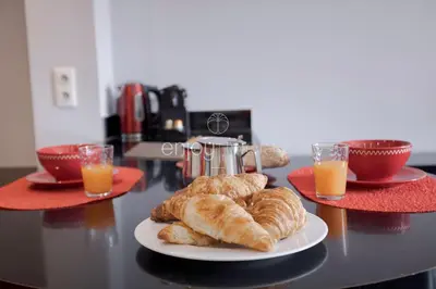a table with a plate of croissants and glasses of orange juice at Palais Miramar - Suite & B31 - Croisette Emplacement Unique - 20M Plage - WIFI - Clim in Cannes