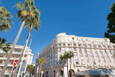 a large white building with palm trees in front of it at Palais Miramar - Suite & B31 - Croisette Emplacement Unique - 20M Plage - WIFI - Clim in Cannes