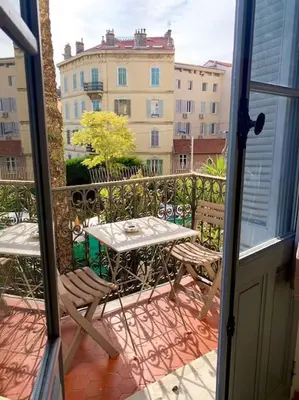 a balcony with a table and chairs and a building at Joli appartement à 5 minutes du palais et plages in Cannes