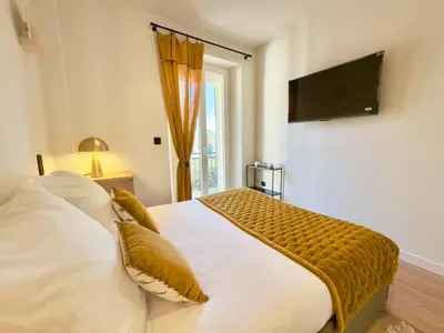 a bedroom with a bed with a television on the wall at Luxueux 3 pièces - 2 chambres avec Terrasse, 4 mn Palais in Cannes