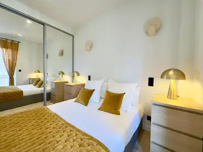 a bedroom with a large bed with white sheets and gold pillows at Luxueux 3 pièces - 2 chambres avec Terrasse, 4 mn Palais in Cannes