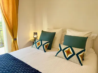 a bedroom with a bed with blue and white pillows at Luxueux 3 pièces - 2 chambres avec Terrasse, 4 mn Palais in Cannes