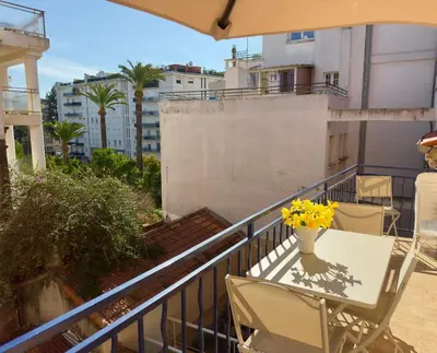 a balcony with a table and chairs and a vase of yellow flowers at Luxueux 3 pièces - 2 chambres avec Terrasse, 4 mn Palais in Cannes
