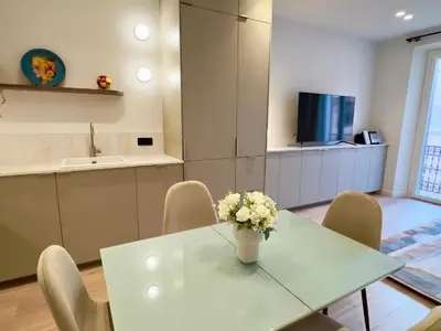 a kitchen with a table with a vase of flowers on it at Luxueux 3 pièces - 2 chambres avec Terrasse, 4 mn Palais in Cannes
