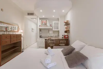 a living room with a white couch and a kitchen at Palais Miramar - Suite & E37 - 20M Plage - Croisette Emplacement Unique - WIFI - Clim in Cannes