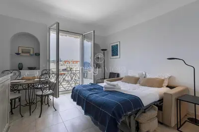 a bedroom with a bed and a table and a balcony at Palais Miramar - Suite & G17 - Vue Mer - Croisette Emplacement Unique -20 Plage - WIFI - Clim in Cannes