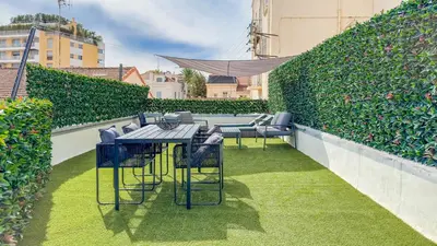 a patio with tables and chairs and a hedge at Le Riviera by Winsome Destination in Cannes