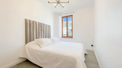 a white bedroom with a bed and a window at Le Riviera by Winsome Destination in Cannes