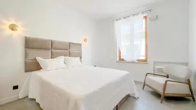a white bedroom with a bed and a chair at Le Riviera by Winsome Destination in Cannes