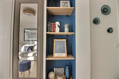 a hallway with blue walls and shelves and a mirror at CENTRAL CANNES in Cannes