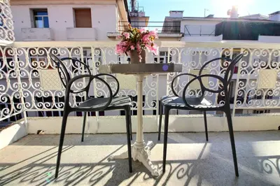 two chairs and a table on a balcony with a vase of flowers at CENTRAL CANNES in Cannes