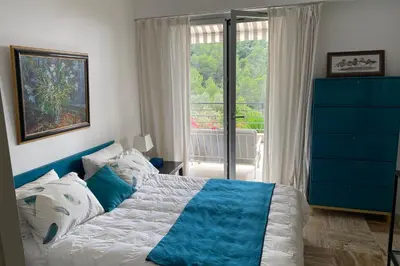 a bedroom with a blue and white bed and a window at Sea View & Large Terrace LIVE IN LA VISTA in Cannes