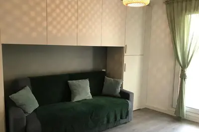 a green couch in a living room with a window at Design studio terrace and beach LIVE IN MARLYNE in Cannes