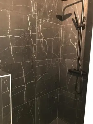 a bathroom with a shower with a marble wall at Design studio terrace and beach LIVE IN MARLYNE in Cannes