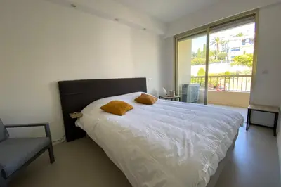 a bedroom with a bed and a chair and a window at Exceptional Cannes Center sea view and swimming pool LIVE IN PARC BRUYERE in Cannes