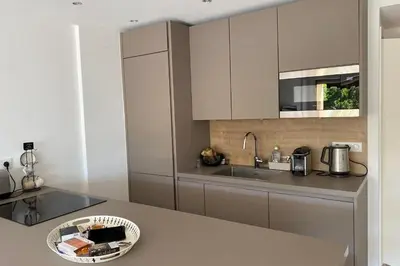 a kitchen with white cabinets and a counter top at Exceptional Cannes Center sea view and swimming pool LIVE IN PARC BRUYERE in Cannes