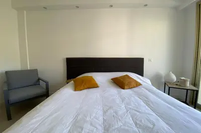 a bed with two pillows and a chair in a bedroom at Exceptional Cannes Center sea view and swimming pool LIVE IN PARC BRUYERE in Cannes