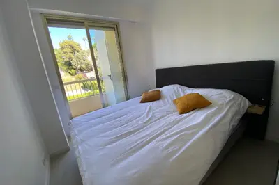 a bedroom with a bed with white sheets and a window at Exceptional Cannes Center sea view and swimming pool LIVE IN PARC BRUYERE in Cannes
