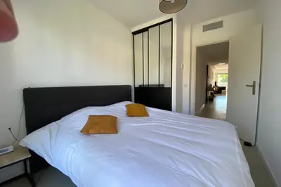 a large white bed with two brown pillows on it at Exceptional Cannes Center sea view and swimming pool LIVE IN PARC BRUYERE in Cannes