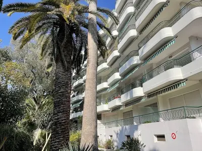 a large building with palm trees in front of it at Cannes 100 mètres de la plage, entièrement climatisé in Cannes