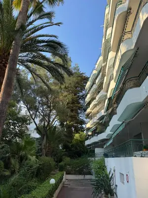 a building with palm trees next to a street at Cannes 100 mètres de la plage, entièrement climatisé in Cannes