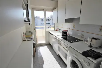 a white kitchen with a washer and dryer in it at Appartement 80 m2 au centre-ville de Cannes in Cannes