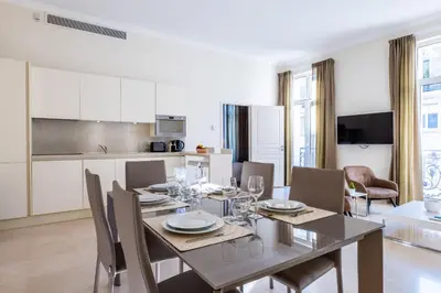 a dining room with a table and chairs and a kitchen at 2-Br steps from the Palais des Festivals in Cannes