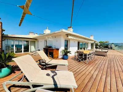 a deck with chairs and a table and a house at Superbe Penthouse avec vue panoramique sur la mer in Cannes