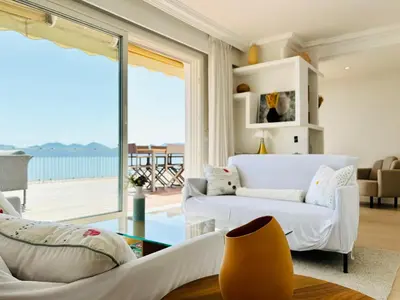 a living room with a white couch and a large window at Superbe Penthouse avec vue panoramique sur la mer in Cannes
