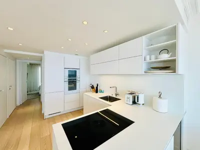 a kitchen with white cabinets and a black counter top at Superbe Penthouse avec vue panoramique sur la mer in Cannes