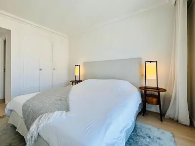 a white bedroom with a bed and two lamps at Superbe Penthouse avec vue panoramique sur la mer in Cannes