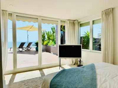 a bedroom with a bed and a television and a balcony at Superbe Penthouse avec vue panoramique sur la mer in Cannes