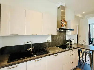 a kitchen with white cabinets and a black counter top at Superbe Villa - Cannes Centre -Proche Palais des Festivals et Plages in Cannes