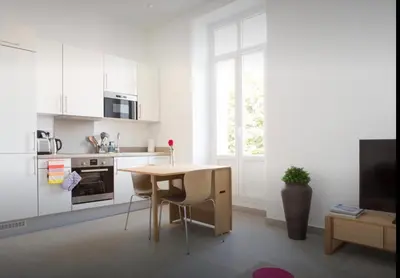 a white kitchen with a table and chairs in a room at La Croisette in Cannes