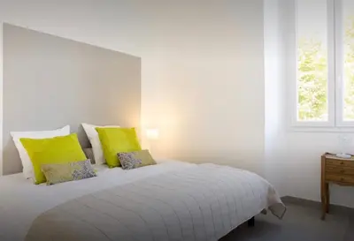 a white bedroom with a bed with yellow pillows at La Croisette in Cannes