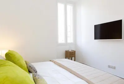 a white living room with a television on a wall at La Croisette in Cannes